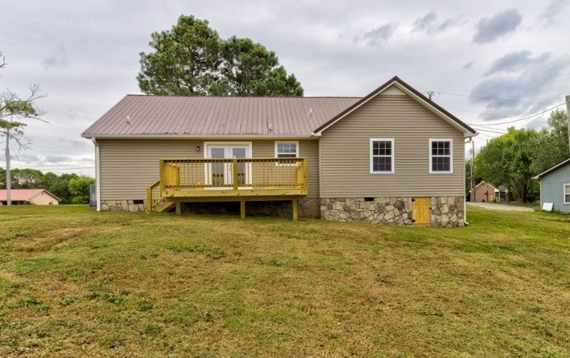 Back exterior of a Chattanooga home with a newly-built wood deck and stone-skirted foundation