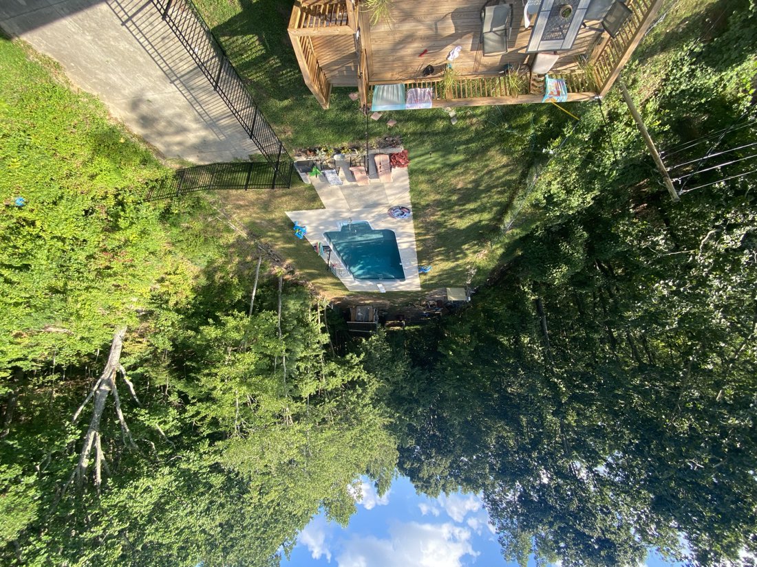 Finished pool with stone surround and wood deck in a wooded Chattanooga backyard